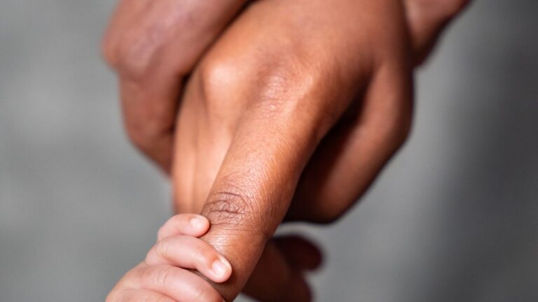 Petite main de nouveau-né tenant le doigt de sa maman
