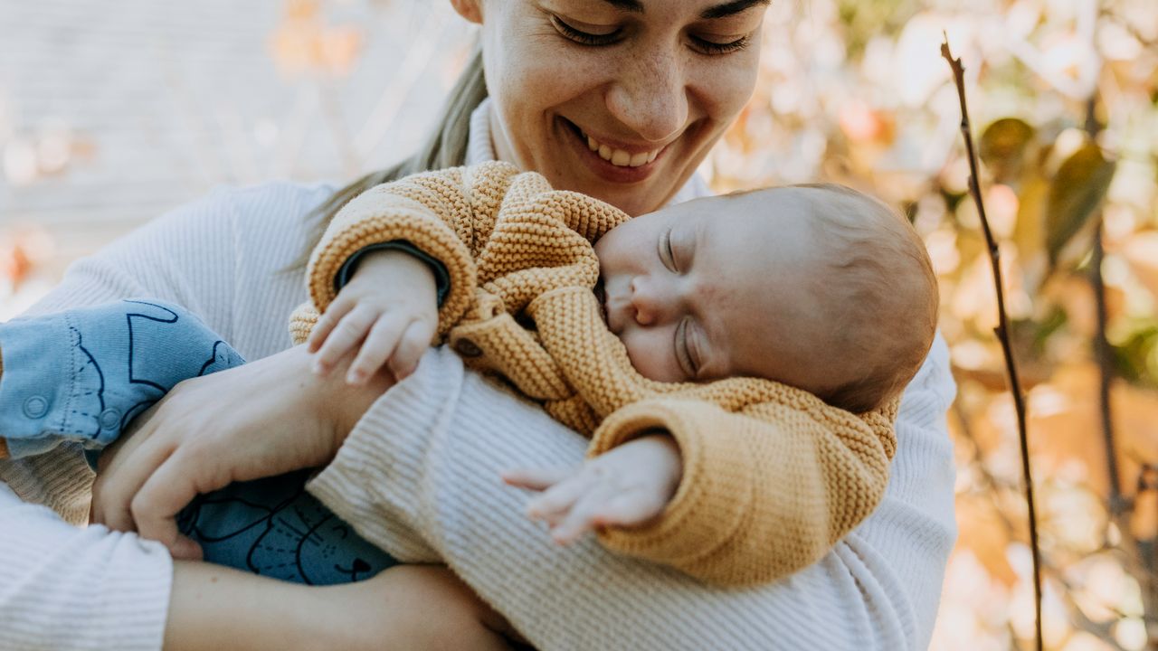 Maman souriante tenant son bébé endormi