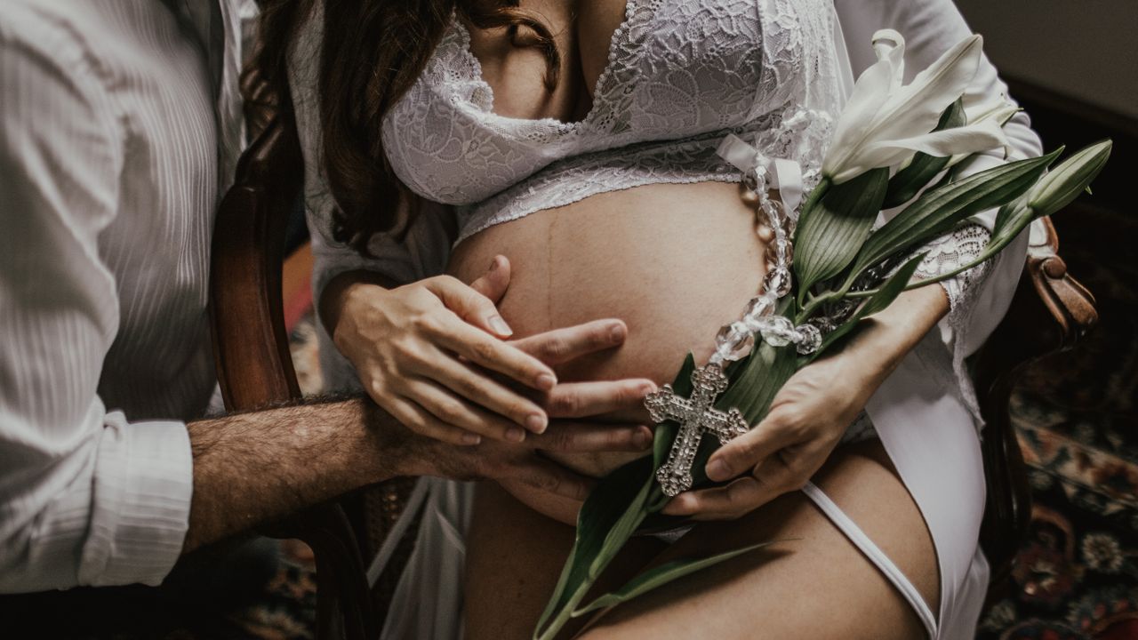 Futurs parents main dans la main sur le ventre, prêts pour le départ à la maternité