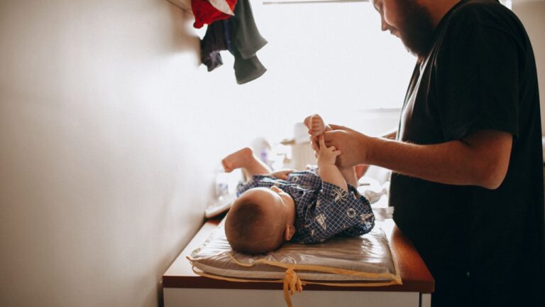 Jeune papa prenant soin de son nouveau-né sur la table à langer