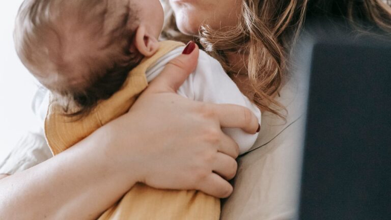 Jeune maman pensive tenant son nouveau-né dans les bras, période du post-partum