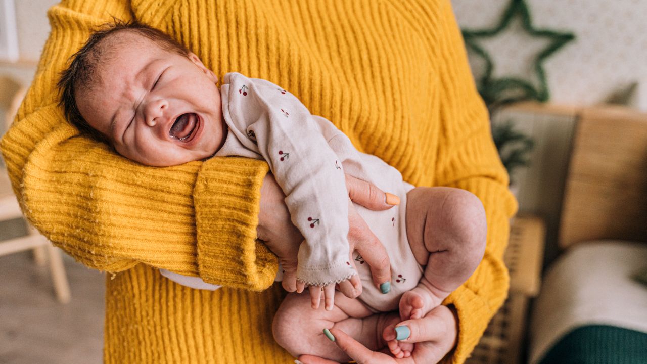 Maman réconfortant son bébé qui pleure pendant une crise de coliques du soir