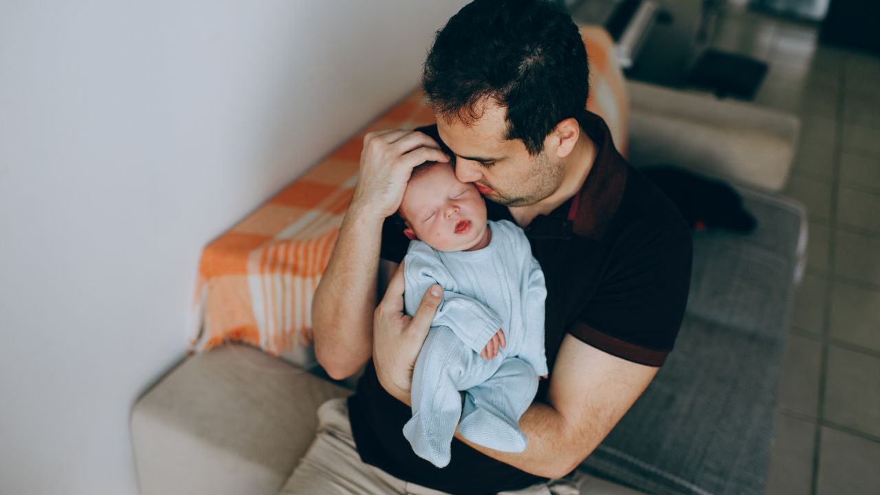 Papa berçant son bébé endormi dans ses bras la nuit
